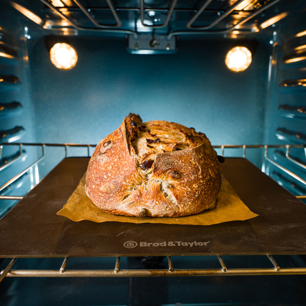 A loaf of sourdough bread baking on a bread steel in the oven.